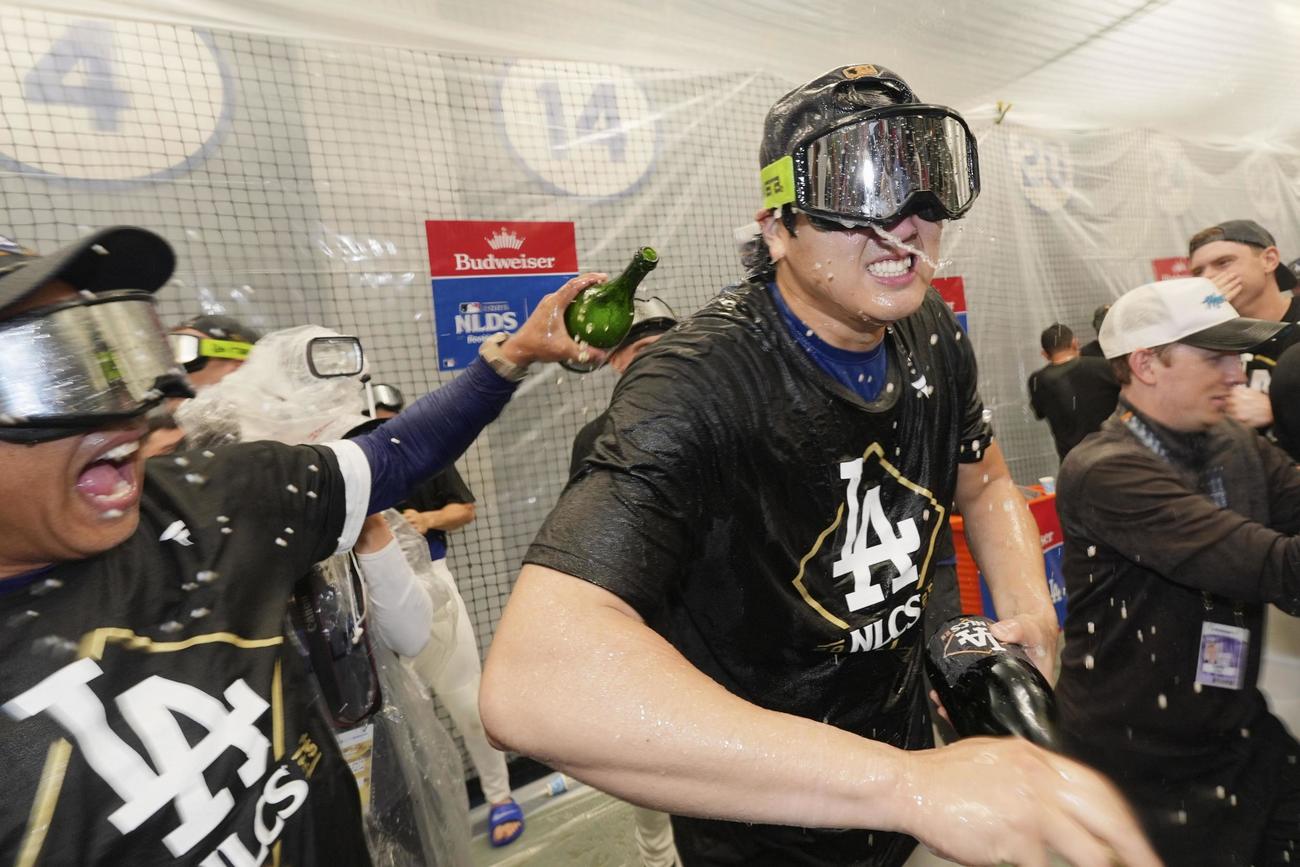 リーグ優勝決定シリーズ進出を決め、祝勝会ではしゃぐドジャースのロバーツ監督（左）と大谷（中央）（AP＝共同）