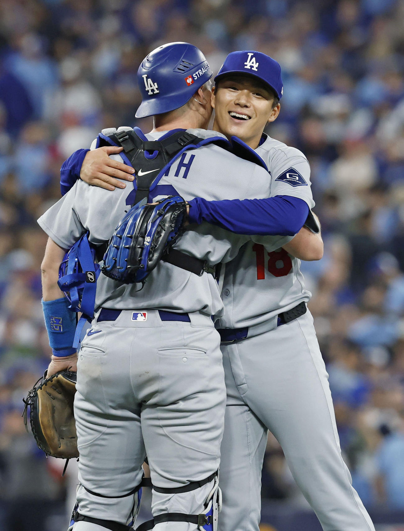 米大リーグ、ブルージェイズとのワールドシリーズ第2戦で完投勝利を挙げ、捕手スミスと抱き合うドジャースの山本由伸＝25日、トロント（共同）