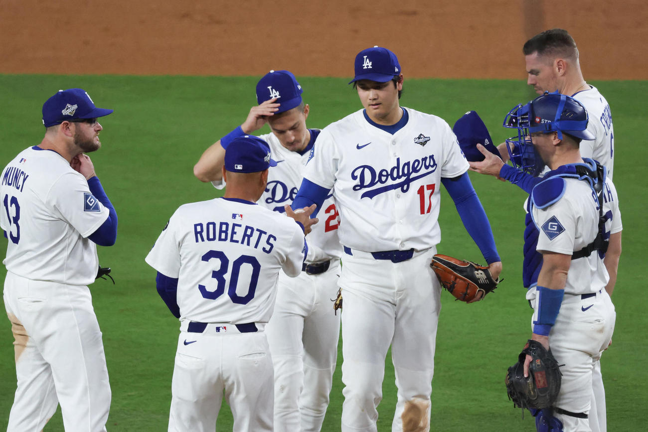 先発したドジャース大谷翔平（中央）は７回途中で降板となり、ボールをロバーツ監督に手渡した（ロイター）