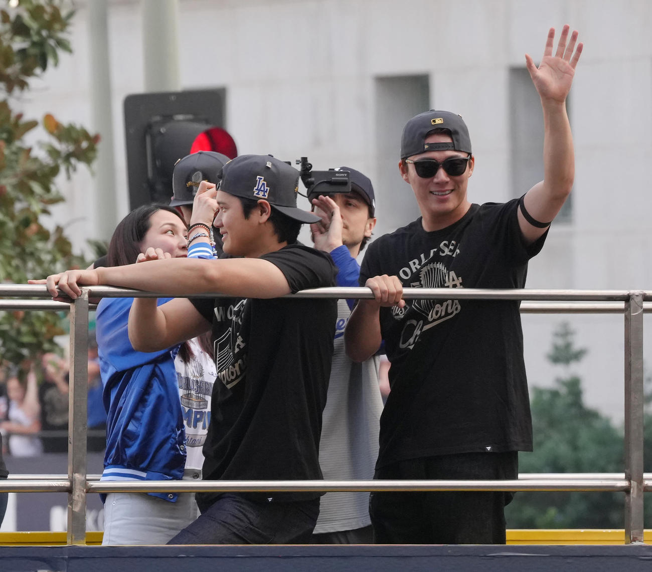 優勝パレードで沿道のファンに手を振るドジャース大谷と山本（右）。左は撮影する真美子夫人（撮影・菅敏）