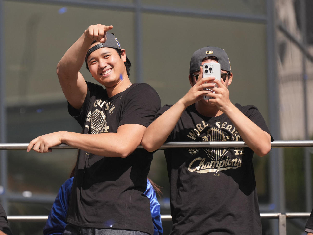 大谷翔平（左）と優勝パレードに集まった観衆の声援に手を振って応え、山本由伸はスマートフォンで撮影をする場面もあった（ロイター）