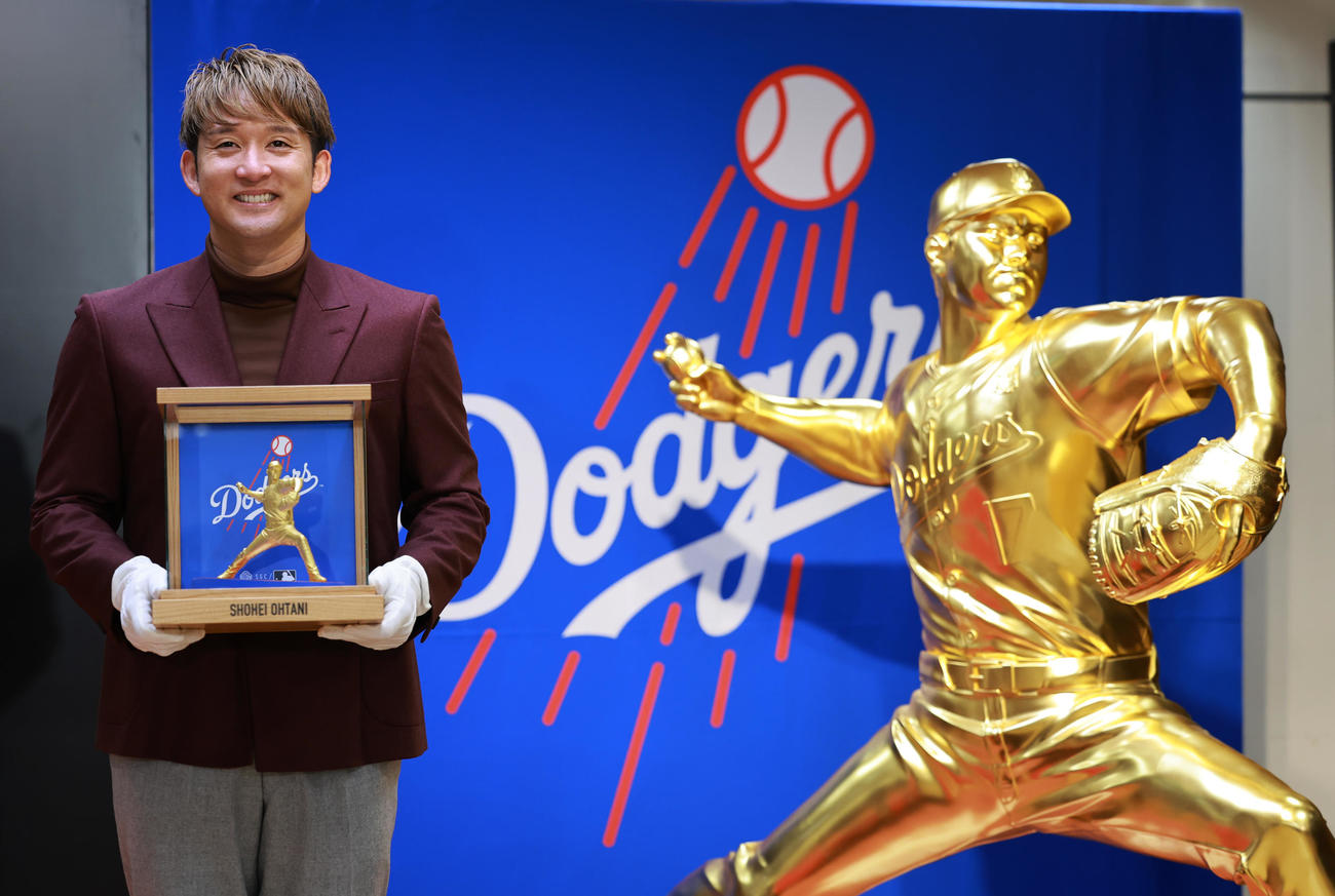 日本橋三越本店の大黄金展で披露された「黄金のピッチャー大谷翔平」の像の横で、純金フィギュアを手にする杉谷拳士氏（撮影・野上伸悟）
