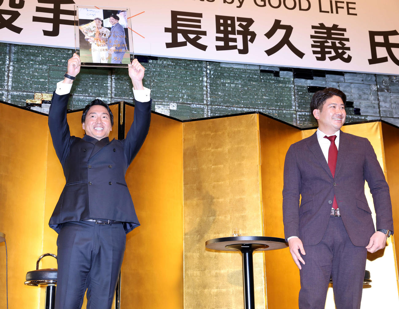 スペシャルトークショーで菅野（右）からサイン入りの2人の写真を贈られ笑顔で掲げる長野久義氏（撮影・浅見桂子）