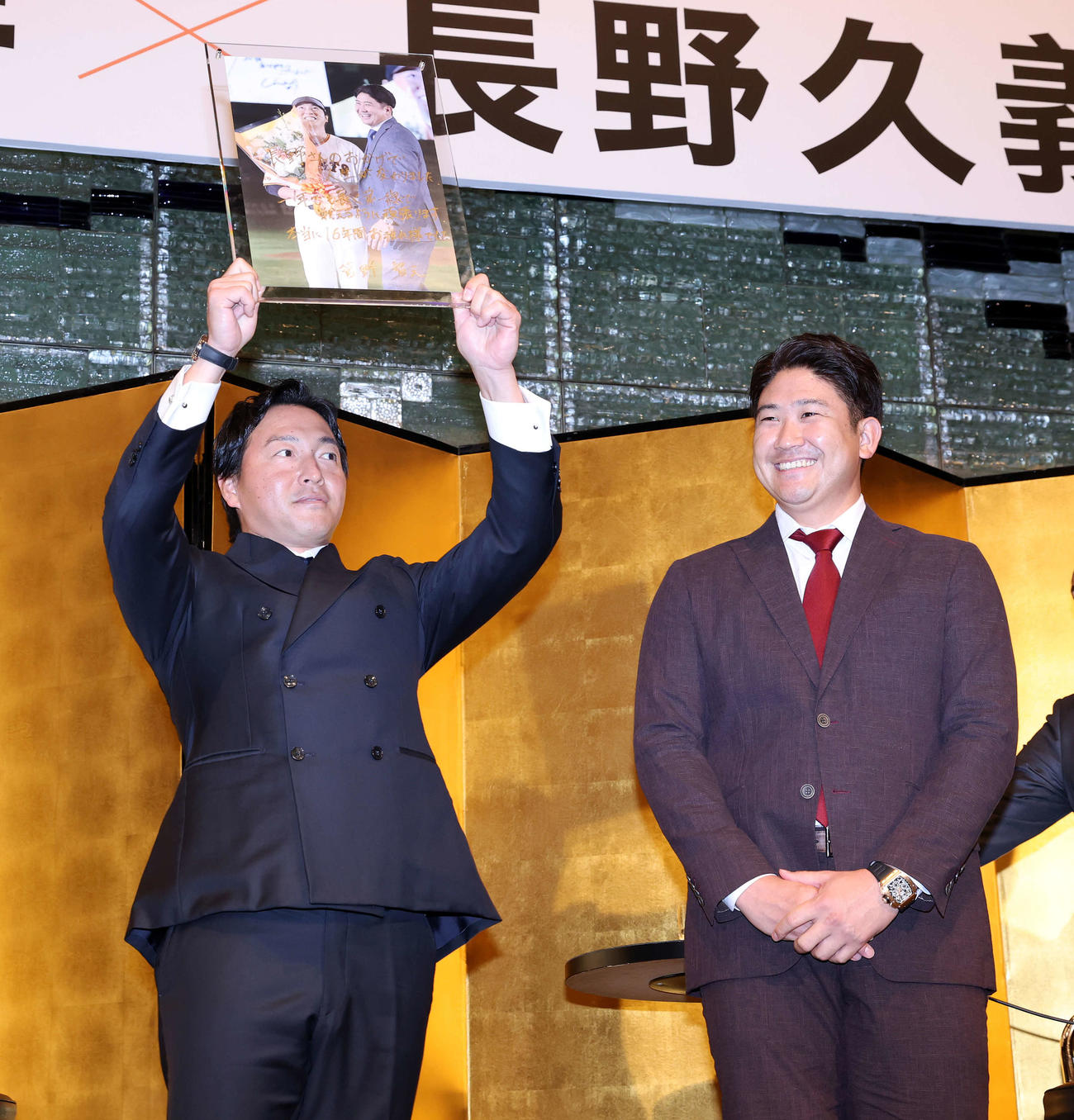 スペシャルトークショーで菅野（右）からサイン入りの2人の写真を贈られ笑顔で掲げる長野久義氏（撮影・浅見桂子）