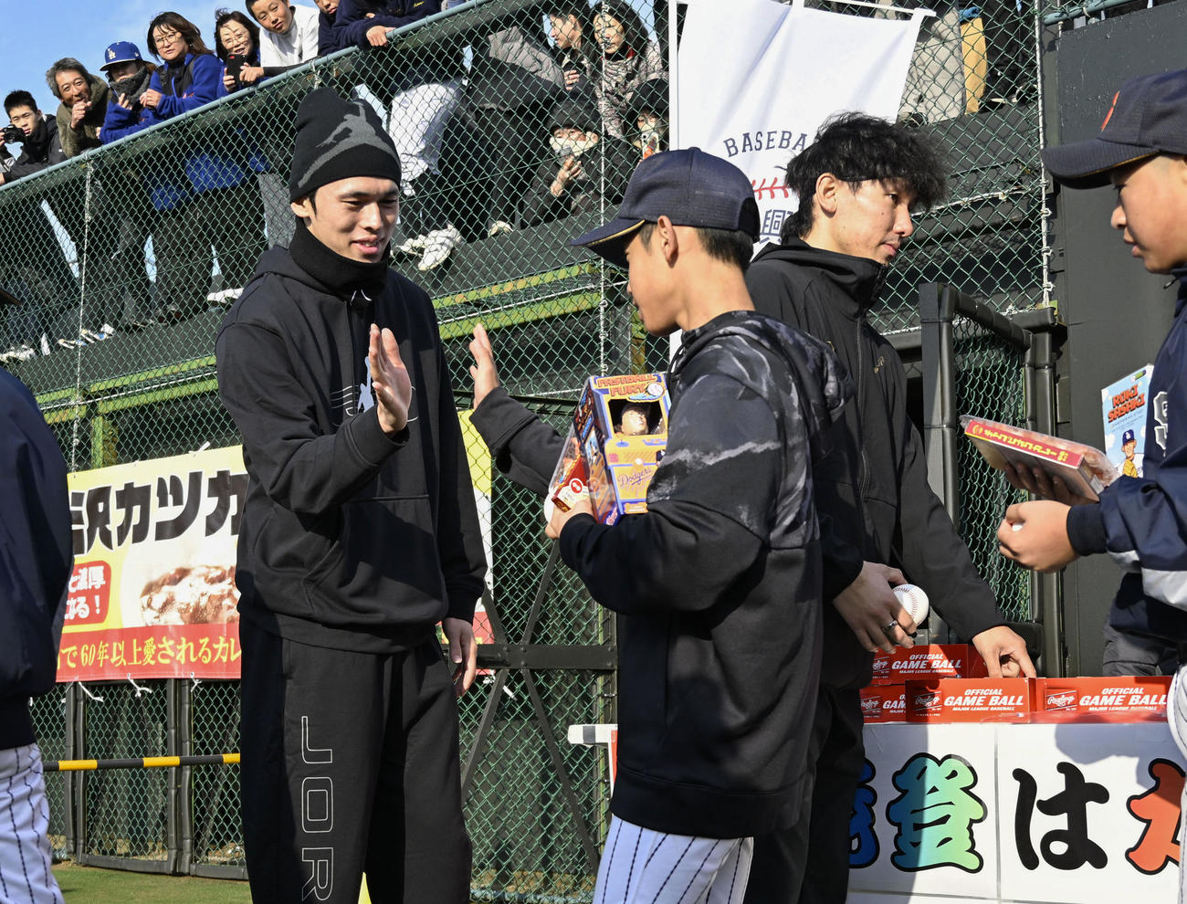 野球教室の参加者とタッチを交わす佐々木朗希投手（左）。右はサインボールを手渡す高野脩汰投手（共同）