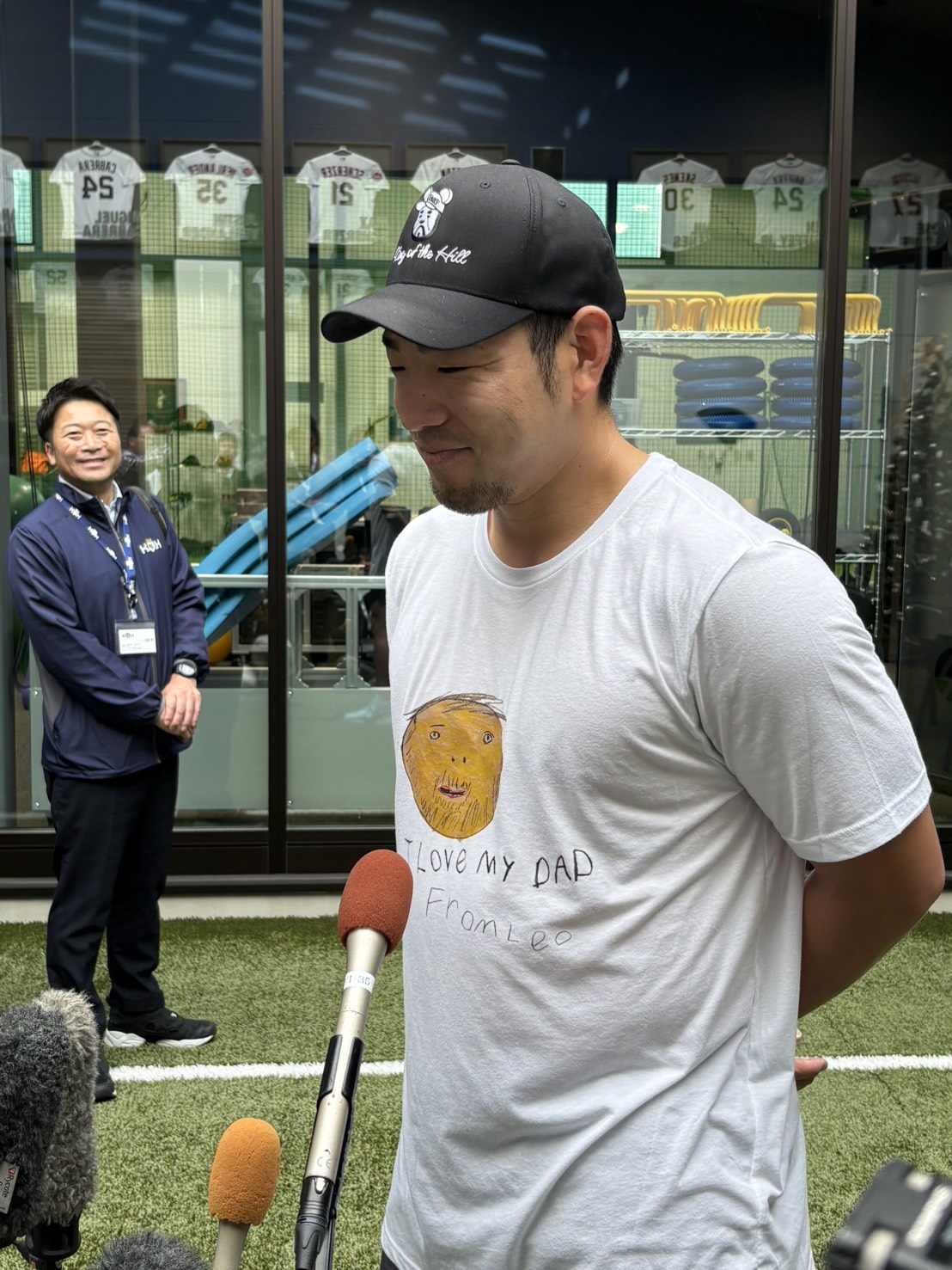 長男レオ君が描いたパパの似顔絵Tシャツで取材を受けるエンゼルス菊池（撮影・久保賢吾）
