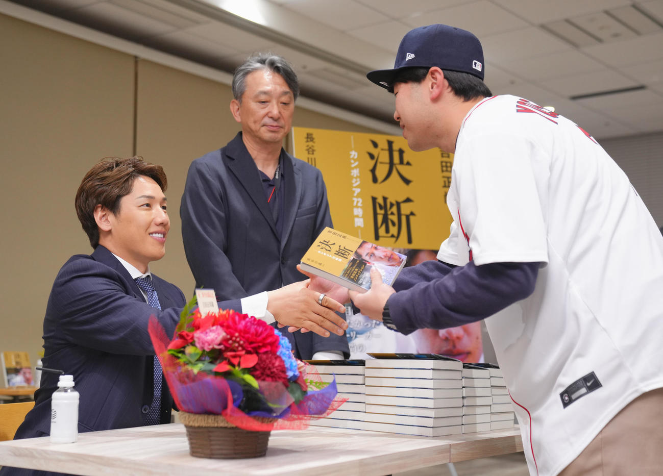 吉田正尚・長谷川晶一氏著書主婦の友社「決断－カンボジア72時間－」出版記念トークショー＆サイン本お渡し会でファンにサイン本を手渡すレッドソックス吉田（左）（撮影・垰建太）
