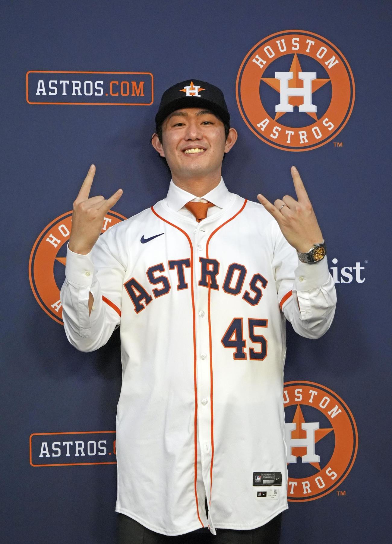 米大リーグ、アストロズの入団記者会見でユニホームに袖を通し、ポーズをとる今井＝１月５日（共同）