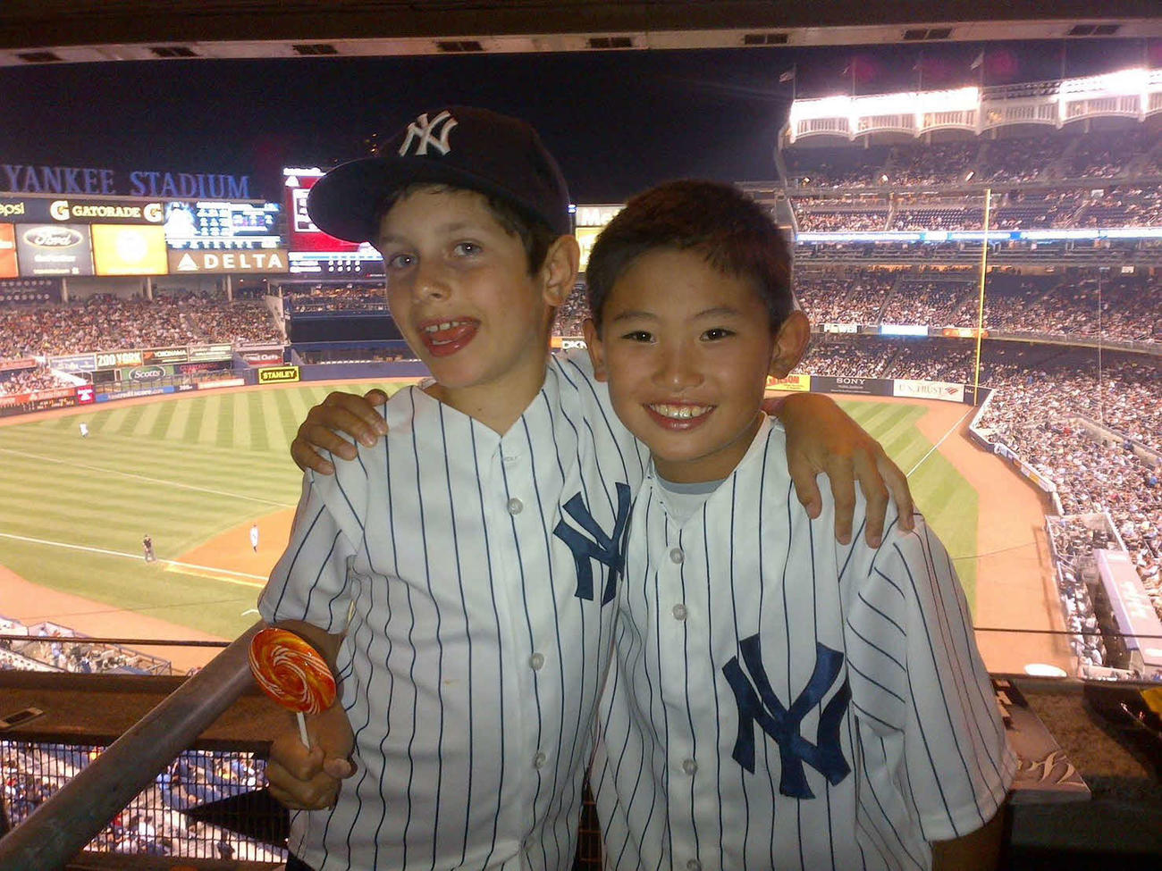 米国時代の友人とヤンキーススタジアムで試合観戦する常松(家族提供)