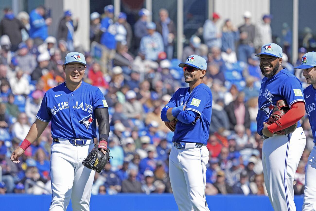 メッツ戦で投手交代の合間にチームメートと笑顔で言葉を交わすブルージェイズ・岡本（左）＝ダンイーデン（共同）