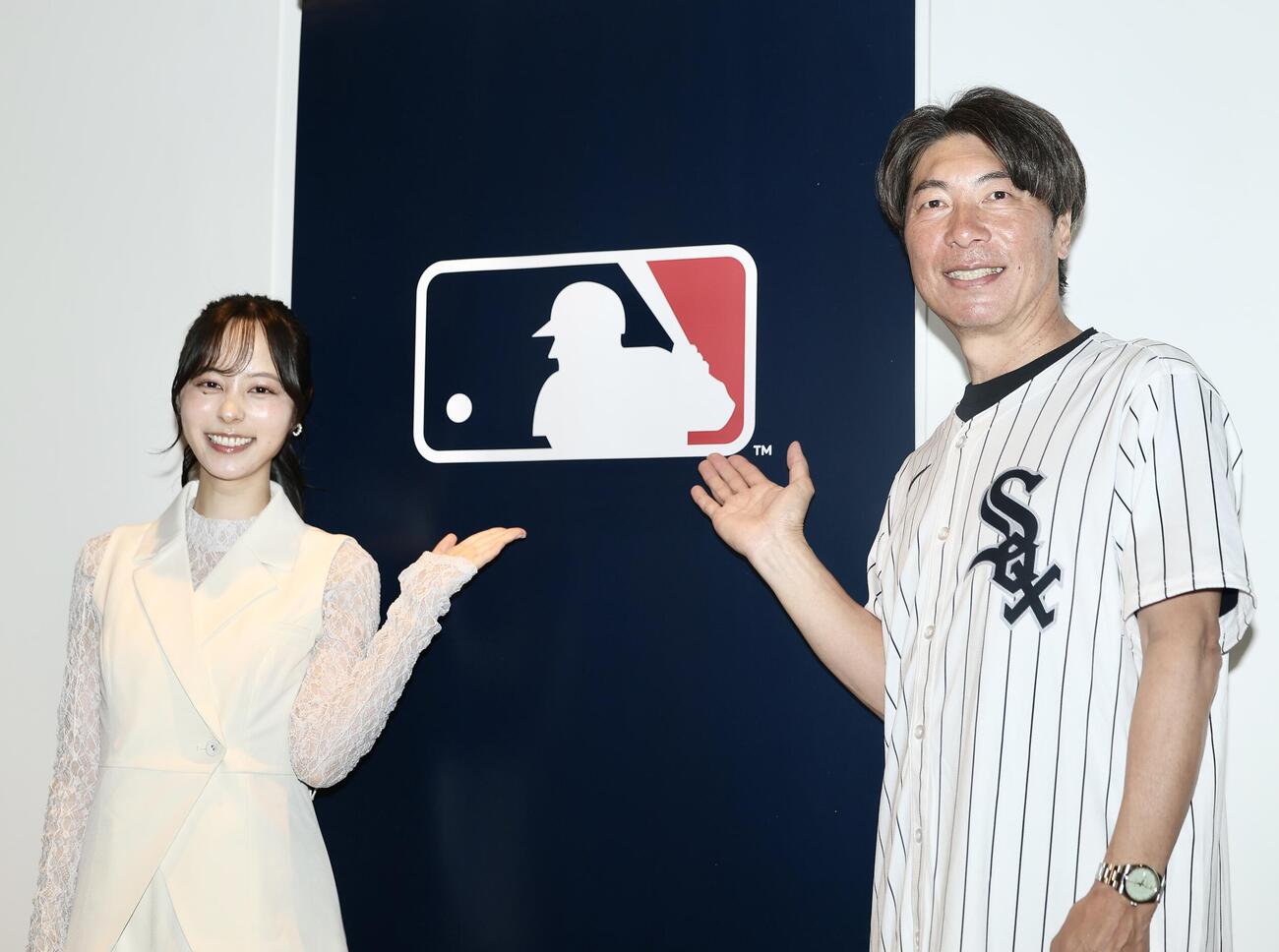 MLBロゴの前で写真に納まる高津臣吾氏（右）とMCの山本萩子（撮影・河田真司）