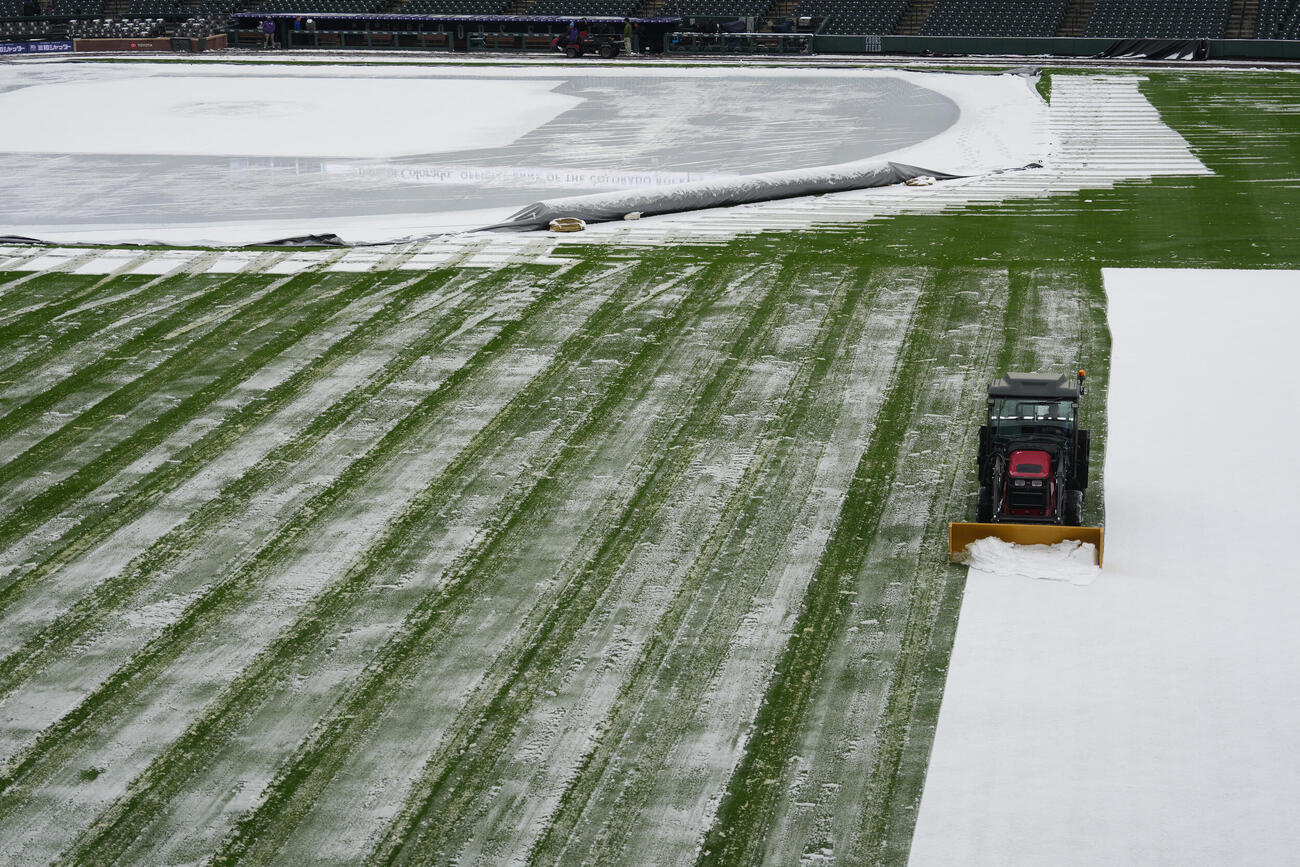 ドジャースとロッキーズの試合前にクアーズ・フィールドの外野の雪を取り除くグラウンドスタッフ (AP）