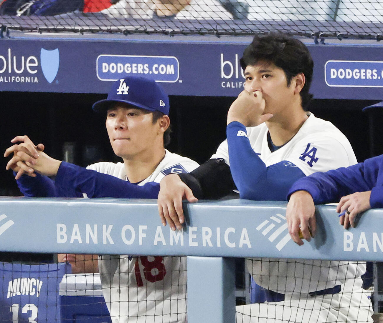 ジャイアンツ戦の7回、ベンチから試合を見つめるドジャース山本（左）と大谷（共同）