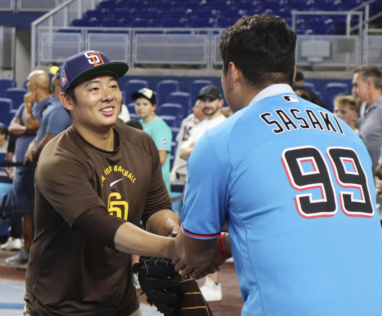 試合前練習を見学し、パドレス・松井（左）と握手を交わすマーリンズの佐々木麟太郎＝24日、マイアミ（共同）