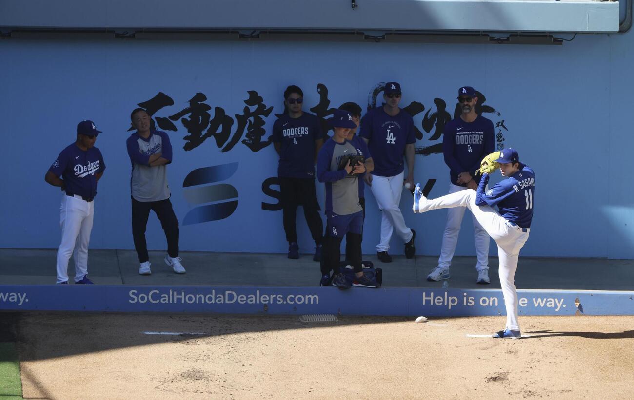 ブルペンで投球練習するドジャース・佐々木朗。左端はロバーツ監督＝ロサンゼルス（共同）