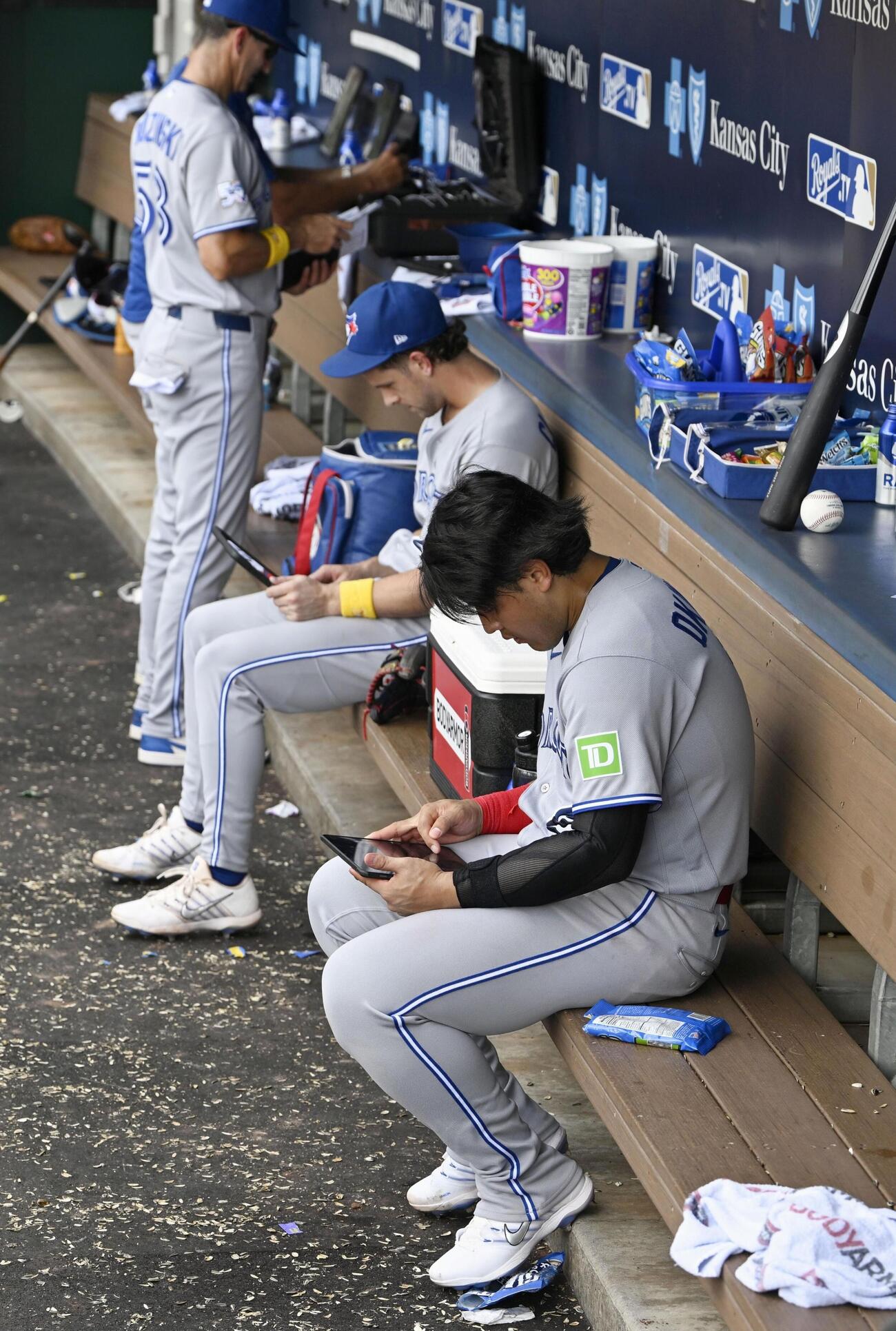 ロイヤルズに敗れ、ベンチでタブレット端末を見るブルージェイズ・岡本（手前）＝カンザスシティー（共同）