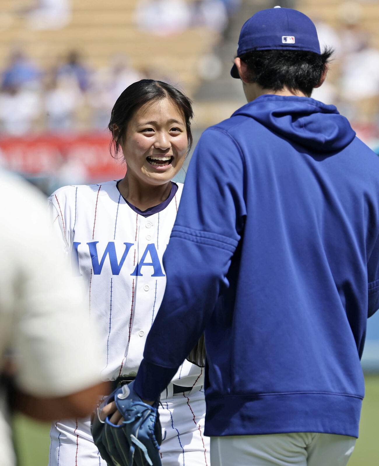 ドジャース－ジャイアンツ戦で始球式を務め、捕手役の佐々木朗（右）と握手を交わす花巻東高の寺本悠里さん＝ロサンゼルス（共同）