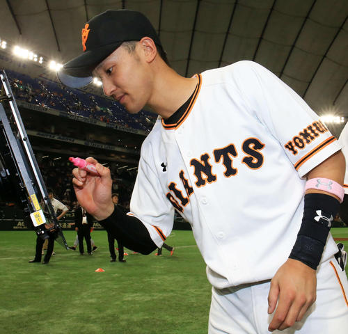 巨人対中日　試合後、ピンク色のリストバントを着けピンクのマジックでサインする巨人吉川尚（撮影・江口和貴）