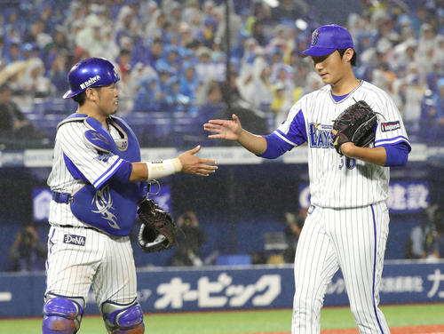 ５回を投げきり、飯塚（右）は戸柱とタッチを交わす（撮影・河野匠）