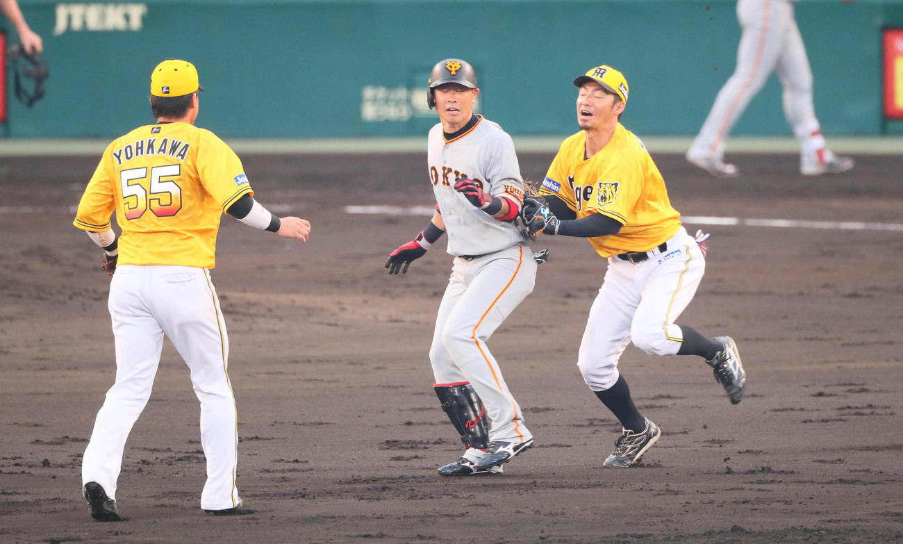 ４回表巨人１死一、二塁、亀井善行は中越え２点先制二塁打を放つが、二、三塁間で挟殺される。右は鳥谷敬（撮影・宮崎幸一）