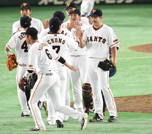 巨人対阪神　完封勝ちした菅野（右）はチームメートとタッチをかわす（撮影・山崎安昭）