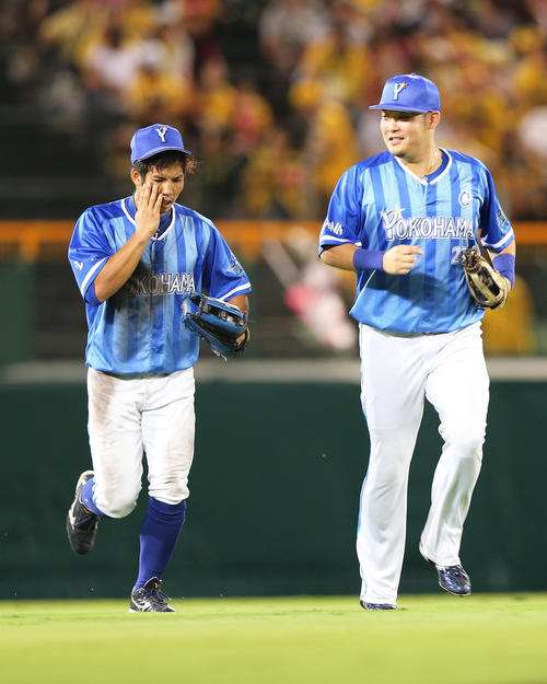 阪神対DeNA　3回裏阪神2死、陽川の中飛をフェンス激突キャッチし顔を抑えながらベンチに帰る桑原（左）。右は筒香（撮影・上山淳一）