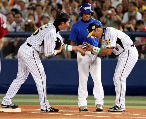 オールスターで右安打を放った新井（左）の手袋を低姿勢で受け取る一塁コーチに立った金本（2008年8月撮影）