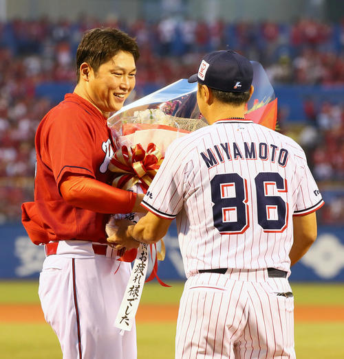 今季での引退を発表ている広島新井(左)は試合前、ヤクルト宮本ヘッドコーチからの花束に笑顔を見せる(撮影・足立雅史)