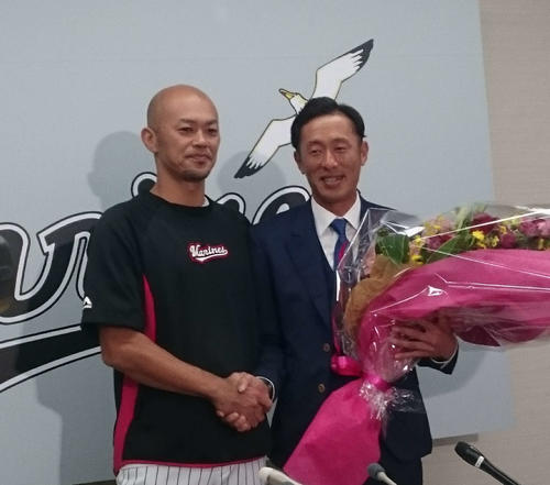 引退会見でサプライズで福浦から花束を渡され、目に涙を浮かべたロッテ岡田（右）