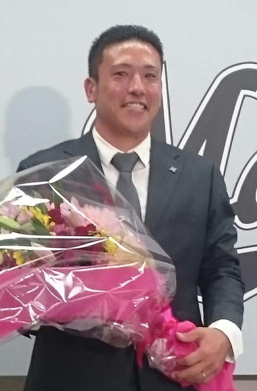 引退会見で花束をもらい、笑顔を見せるロッテ大隣