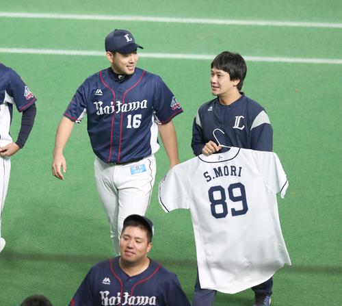 日本ハム対西武 パ・リーグ優勝を決め森コーチのユニホームを持ったスタッフと笑顔で引き揚げる菊池(撮影・黒川智章)