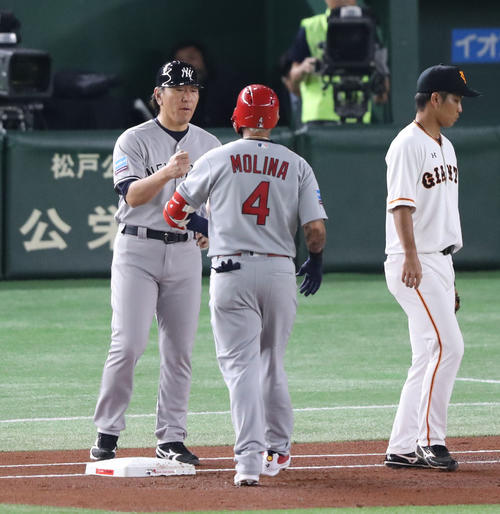 巨人対MLB 1回表MLB1死、中前打を決めたモリーナとグータッチするMLB松井コーチ(撮影・林敏行)