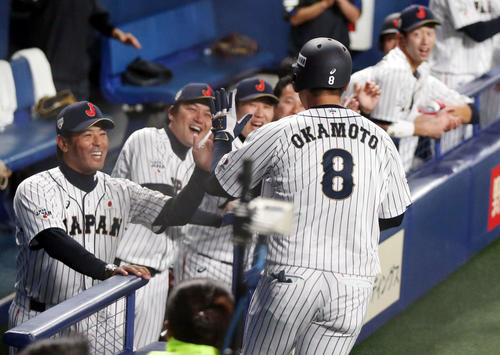 日本対MLB　2回裏日本無死、ソロ本塁打を放った岡本（手前）を笑顔で迎える稲葉監督（左）ら日本ベンチ（撮影・狩俣裕三）