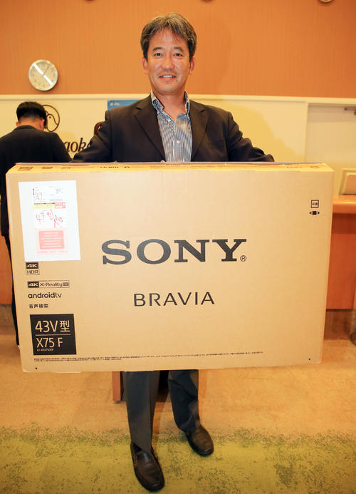 球団納会ゴルフで優勝した潮崎前2軍監督は賞品のテレビを手に笑顔を見せる(撮影・浅見桂子)
