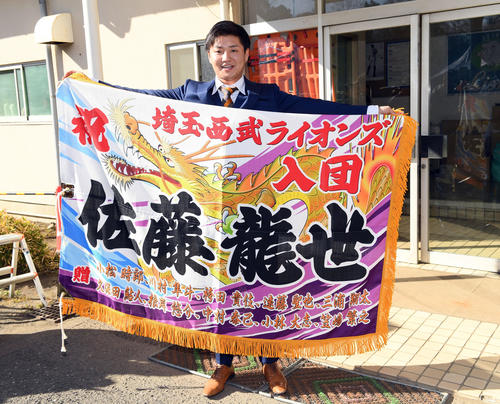 地元の友人から贈られた大漁旗を手に笑顔を見せるドラフト7位の佐藤龍世(撮影・たえ見朱実)