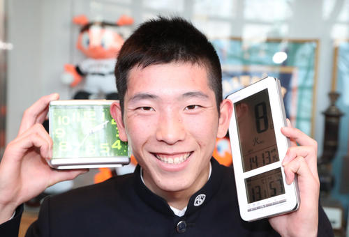 入寮で持ち込んだ目覚まし時計を手にポーズをとる巨人6位の戸郷(撮影・林敏行)