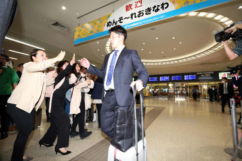 那覇空港に到着し、女性ファンとタッチを交わす吉田輝（撮影・狩俣裕三）