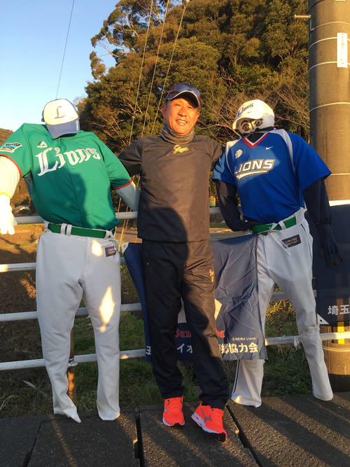 早朝ランニングで道ばたにある西武ユニホームを着たかかしと写る辻監督（撮影・栗田成芳）