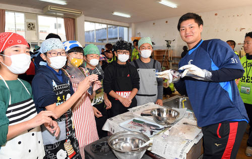 実家が漁業を営む西武佐藤龍世は魚の下ごしらえもお手のもの？地元の小学生とともに食材の「トビウオ」を器用にさばく（撮影・たえ見朱実）
