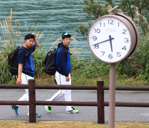 早朝練習か！？時計が5時40分過ぎを表示する中、球場入りする日本ハム吉田輝（右）と柿木。実は時計調整中で、通常の午前8時20分の入りでした（撮影・江口和貴）