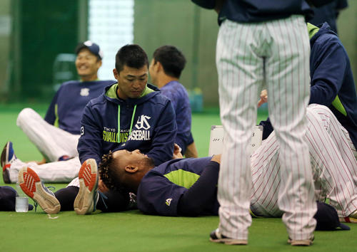 ウオーミングアップで青木宣親(左)の左足をまくらにリラックスするバレンティン(撮影・狩俣裕三)