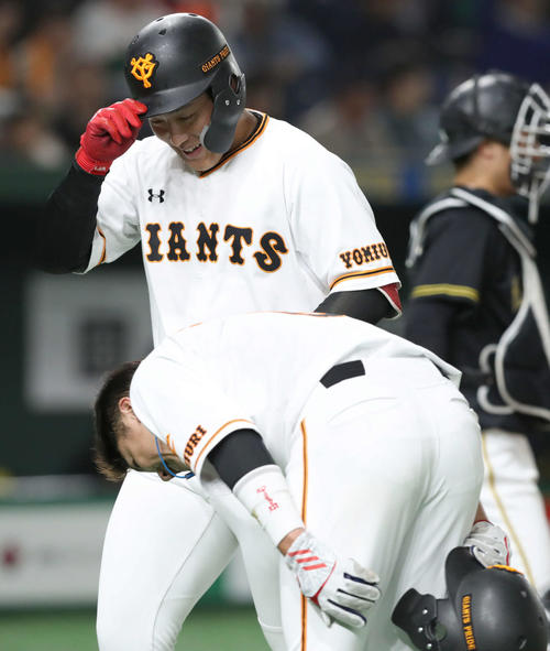 巨人対阪神　1回裏巨人2死一塁、先制中越え2点本塁打の岡本（奥）は頭を深々と下げて迎える一塁走者坂本勇に恐縮する（撮影・松本俊）