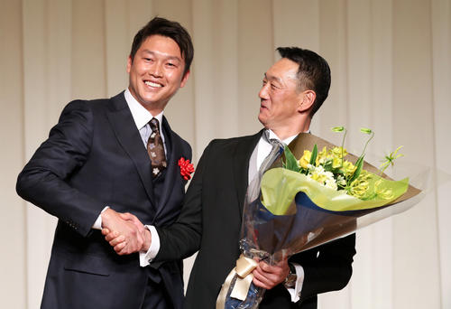 「金本知憲氏　野球殿堂入りを祝う会」で新井貴浩氏（左）から花束を贈られ、思わずのけぞる金本知憲氏（2018年12月11日撮影）