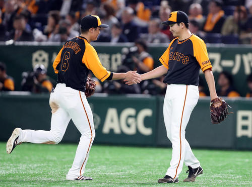 巨人対ヤクルト　6回表を終え、この回に好捕した坂本勇（左）とタッチを交わす菅野（撮影・狩俣裕三）
