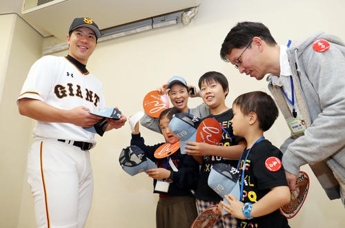巨人対DeNA　難病の子どもたちの支援する活動を行う巨人炭谷（左）は試合前、招待した子どもたちにサインと帽子を笑顔でプレゼントする（撮影・垰建太）