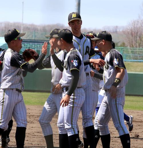 東農大北海道対旭川大　初完封を喜ぶリーグ最長身195センチの旭川大・松村投手（中央）（撮影・永野高輔）