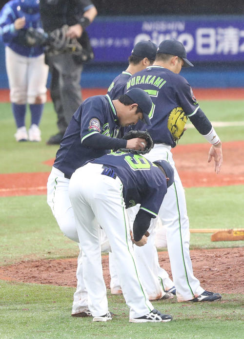 DeNA対ヤクルト　9回裏DeNA2死二塁、田畑コーチ（手前）にスパイクの泥を落としてもらう五十嵐（撮影・河野匠）