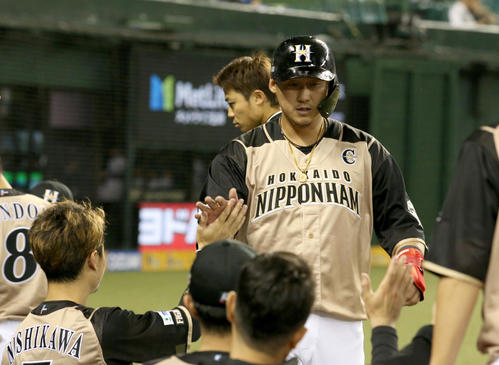 西武対日本ハム　1回表日本ハム2死二塁、田中賢の適時二塁打で生還し、チームメートに出迎えられる中田（撮影・佐藤翔太）