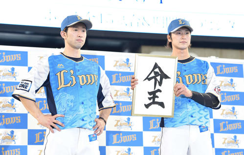 「ライオンズフェスティバルズ2019」期間限定ユニホームを着て、山川が書いた「令王」を掲げる西武金子侑（右）と外崎（撮影・鈴木みどり）