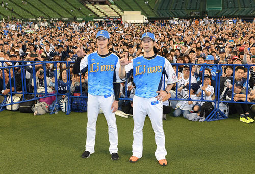「ライオンズフェスティバルズ2019」期間限定ユニホームを着て、山川が書いた「令王」を掲げる西武金子侑（左）と外崎（撮影・鈴木みどり）